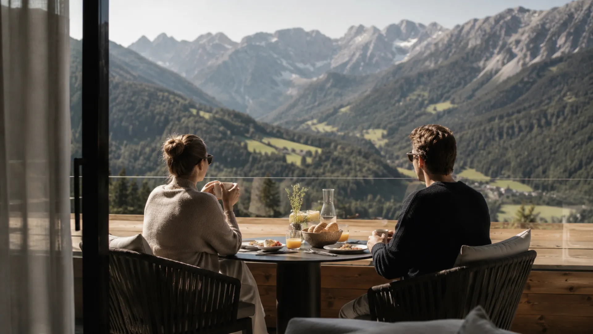 Paar beim Frühstück auf einer Terrasse mit Blick auf die Alpen