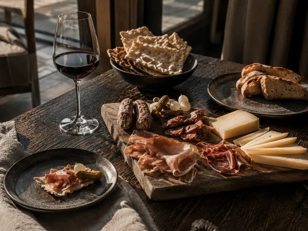 Weniger Inszenierung, mehr Gefühl – Genuss, der nach Berg und Tal schmeckt. Wein, Brot, Käse und Wurstwaren auf einem Holztisch