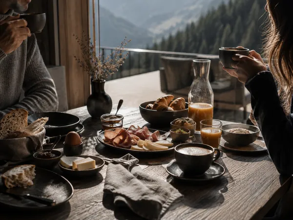 Weniger Inszenierung, mehr Gefühl – Genuss, der nach Berg und Tal schmeckt. Frühstück mit Brot, Käse, Aufschnitt und Kaffee am Tisch mit Bergblick