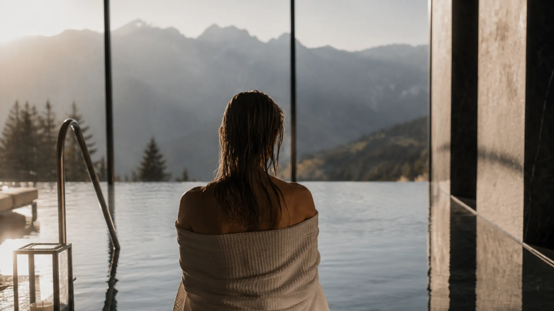 Wo alles langsamer werden darf: der Atem, die Gedanken, der Blick auf den Tag. Person mit Handtuch am Infinity-Pool mit Blick auf Berglandschaft